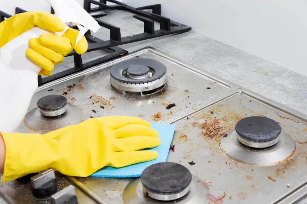 Cleaning a gas stove with kitchen utensils